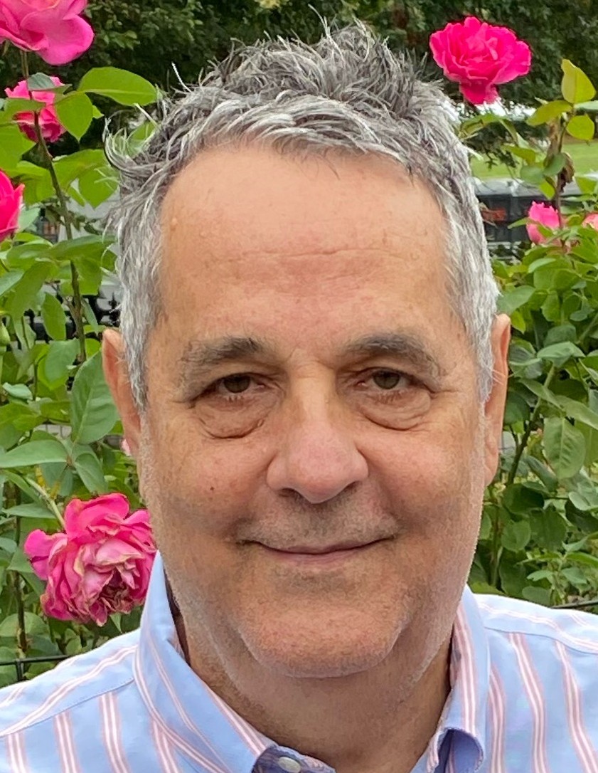 Headshot of David Sicilia in front of bushes with pink flowers.